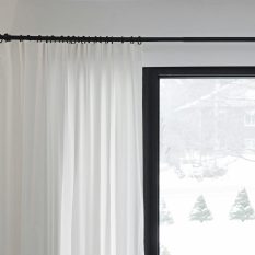 White curtains partially covering a window with a snowy outdoor view. Minimalist home decor.