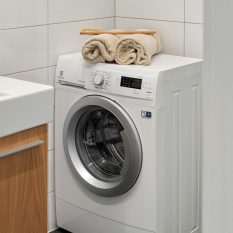 Stylish and clean laundry space featuring a white washing machine with towels on top.