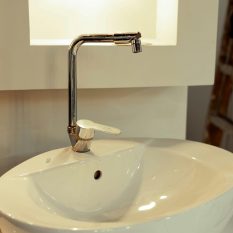 Sleek ceramic sink with a polished stainless steel faucet under ambient lighting.