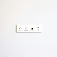A minimalist image showcasing a modern wall outlet array on a bright white wall.