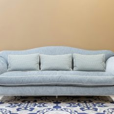 Stylish blue sofa with cushions on patterned carpet, perfect for a modern, cozy living space.