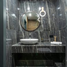 Contemporary bathroom design with marble surfaces and round mirror.